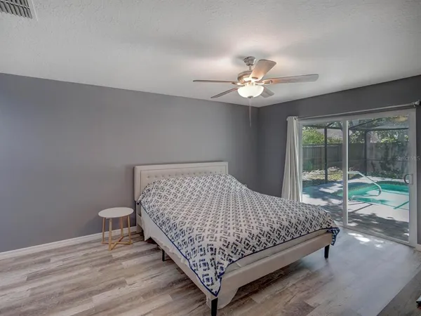 a bedroom with a bed and a large window with ceiling fan