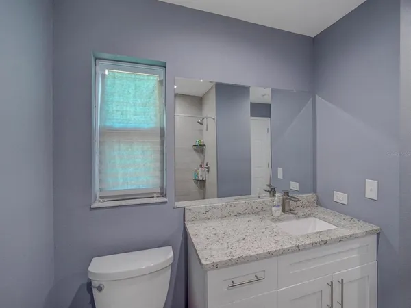 a bathroom with a granite countertop sink a toilet and a window