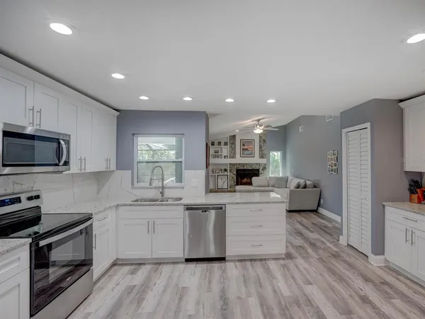 a kitchen with stainless steel appliances a white stove top oven a sink dishwasher and a refrigerator with wooden floor