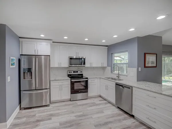 a kitchen with stainless steel appliances granite countertop a refrigerator sink and stove
