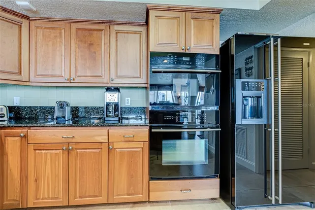 a kitchen with stainless steel appliances kitchen island granite countertop a dining table chairs and a refrigerator