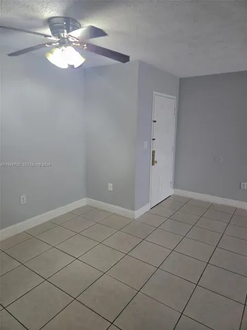 a view of an empty room and chandelier fan