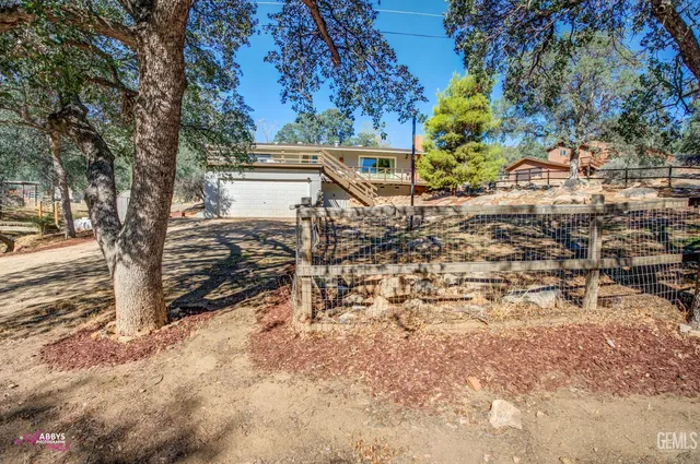 a view of a backyard with wooden fence and large trees