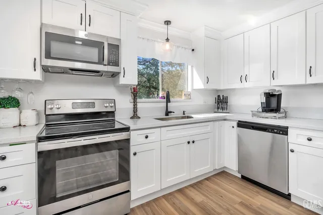 a kitchen with cabinets stainless steel appliances a sink and a window