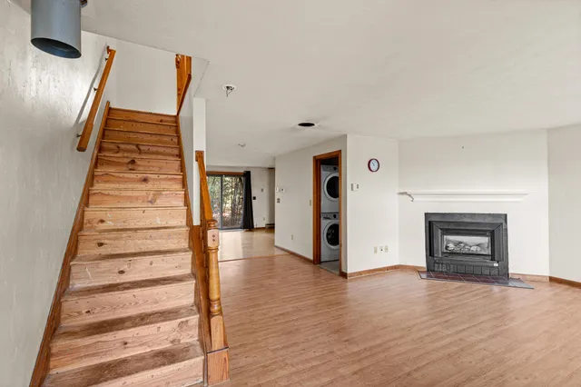 a view of an empty room with wooden floor fireplace and windows