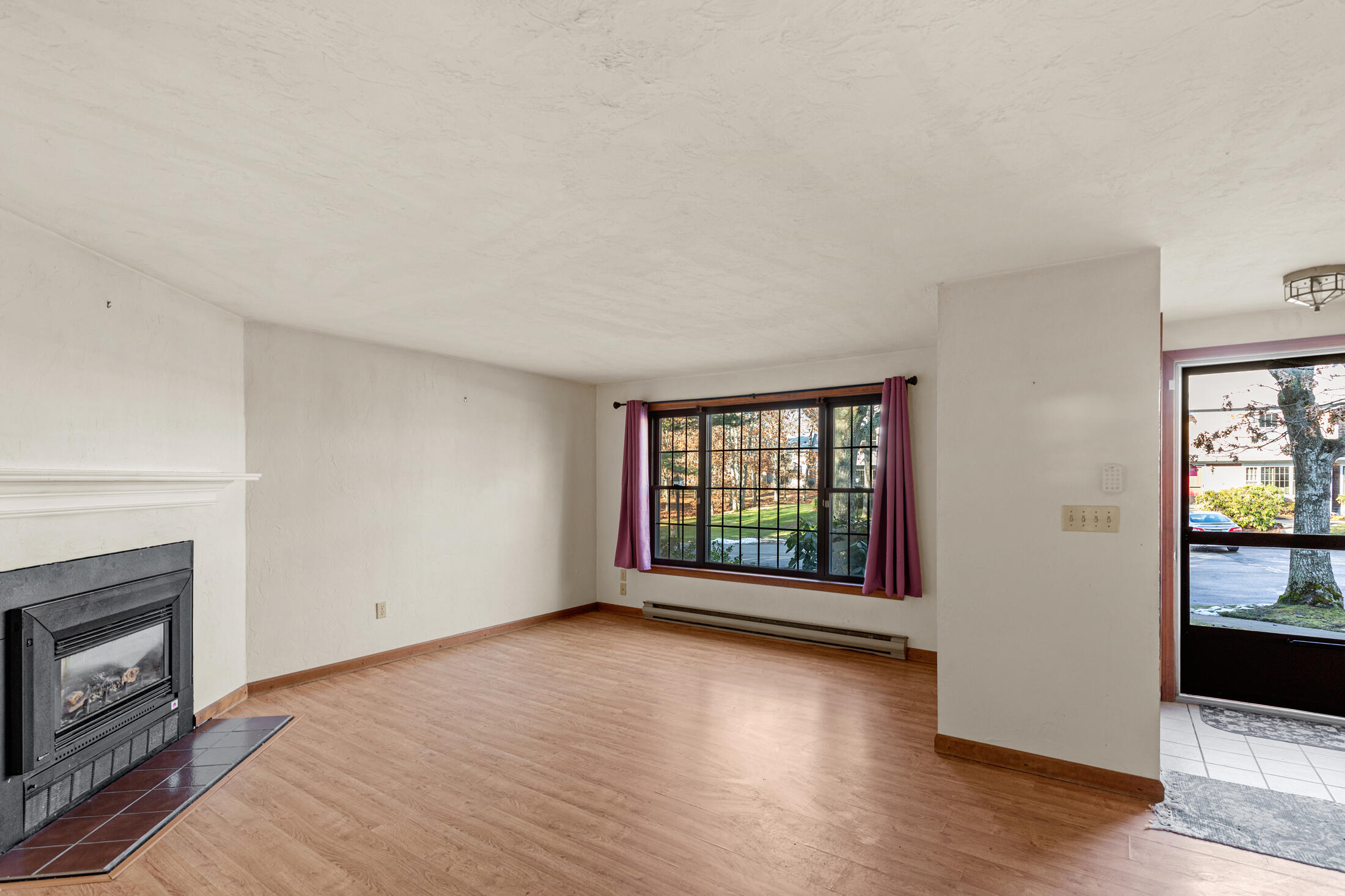 195 Falmouth Road, Unit 19F Mashpee, MA 02649 - Photo 9 of 25 an empty room with wooden floor and fireplace