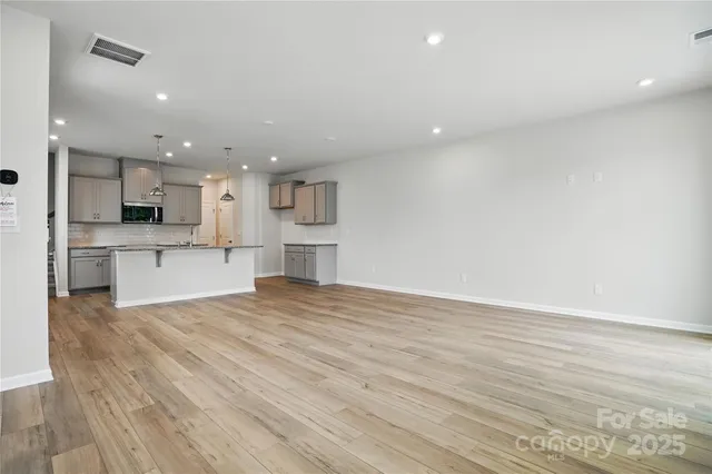 a view of kitchen with kitchen island a sink wooden floor and stainless steel appliances