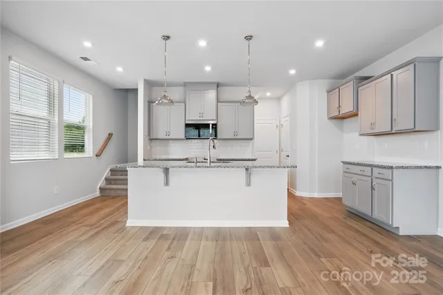 a large white kitchen with kitchen island a sink a center island stainless steel appliances and a counter space