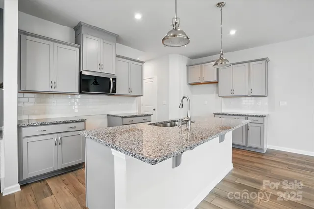 a kitchen with stainless steel appliances granite countertop a sink a stove and microwave