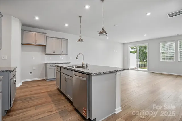 a kitchen with stainless steel appliances granite countertop a sink a stove and a wooden floors