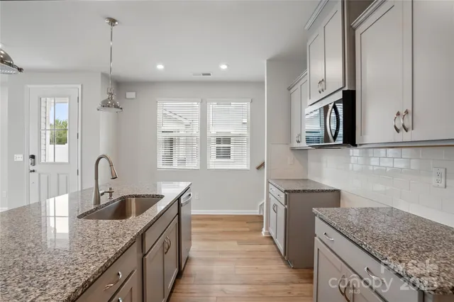 a kitchen with stainless steel appliances granite countertop a sink dishwasher stove and oven