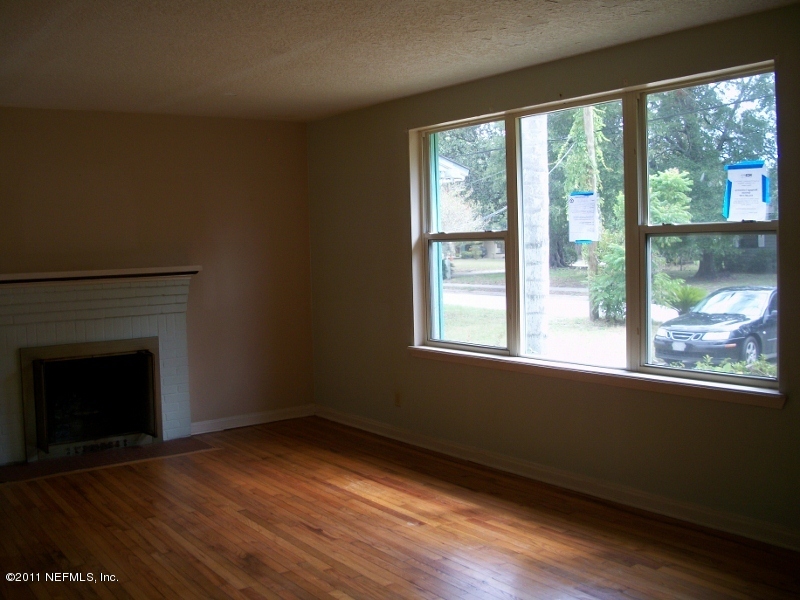 5514 Stetson Road Jacksonville, FL 32207 - Photo 4 of 9 an empty room with wooden floor fireplace and windows
