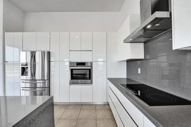 a kitchen with granite countertop a refrigerator and a stove top oven