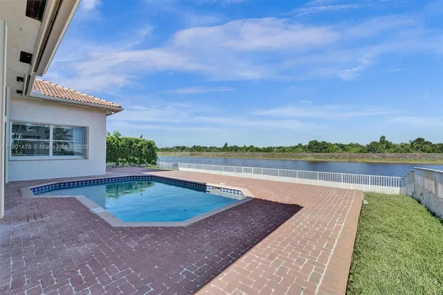 a view of a garden with lake and houses in the back