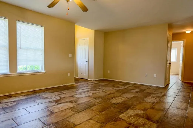 a view of an empty room with window and a chandelier fan