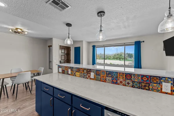 a living room with stainless steel appliances granite countertop a sink a counter space and a chandelier