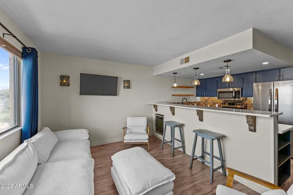 a living room with stainless steel appliances furniture a dining table and a window