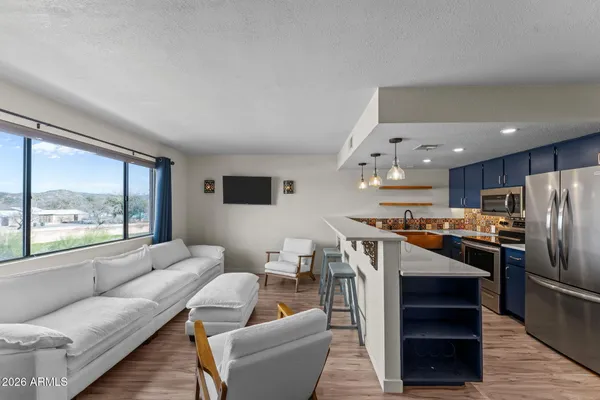 a living room with stainless steel appliances kitchen island furniture and a large window