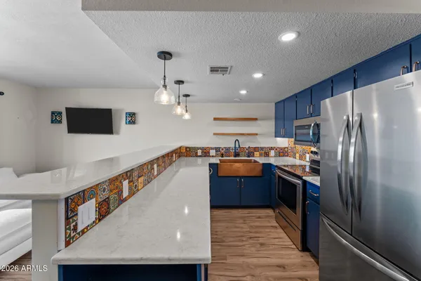 a kitchen with stainless steel appliances granite countertop a refrigerator a oven a sink and a dining table with wooden floor