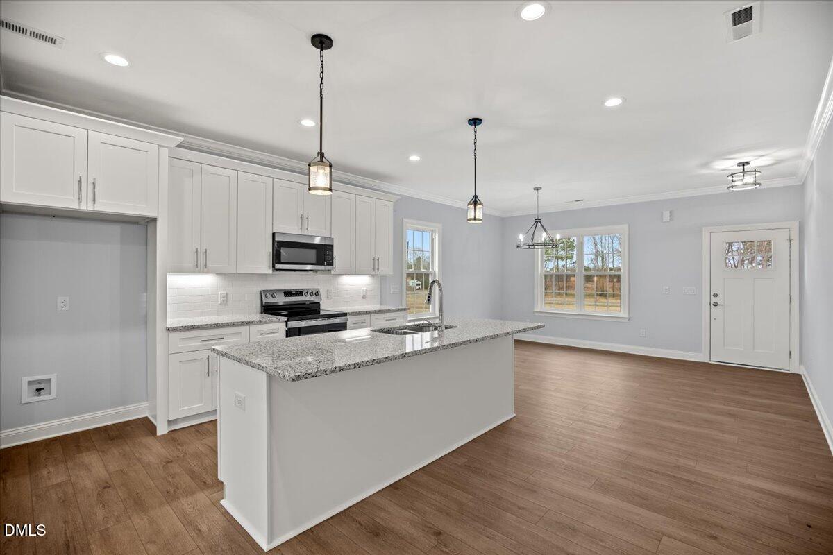 1300 Nick Coley Road Whitakers, NC 27891 - Photo 17 of 47 a kitchen with stainless steel appliances granite countertop a sink a stove a refrigerator and white cabinets with wooden floor
