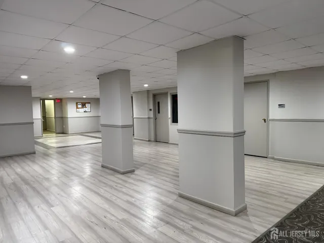 a view of empty room with wooden floor and kitchen