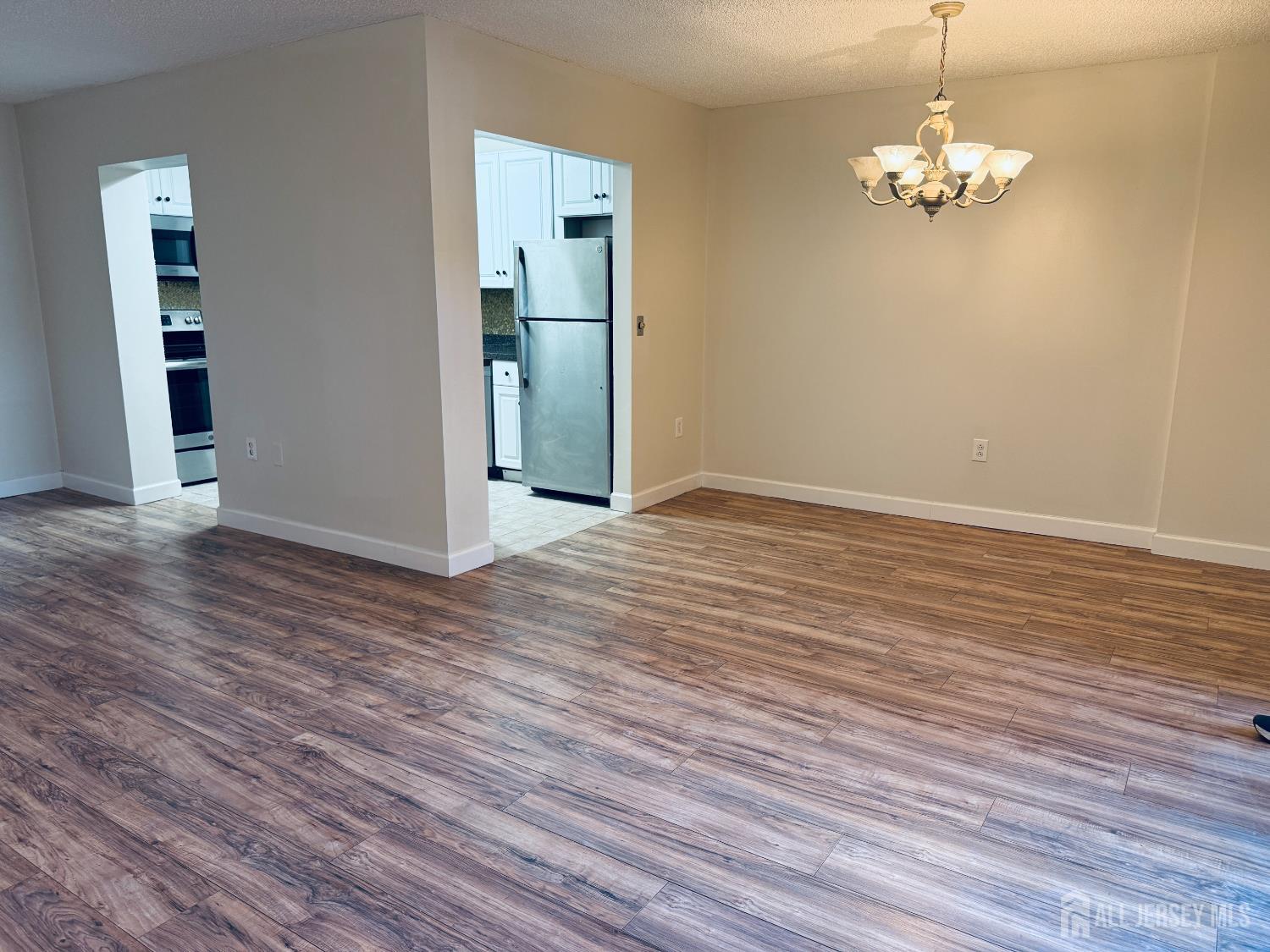 10 North Wood Avenue, Unit 314 Linden, NJ 07036 - Photo 3 of 18 an empty room with wooden floor chandelier and windows