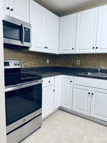 a kitchen with granite countertop white cabinets and stainless steel appliances