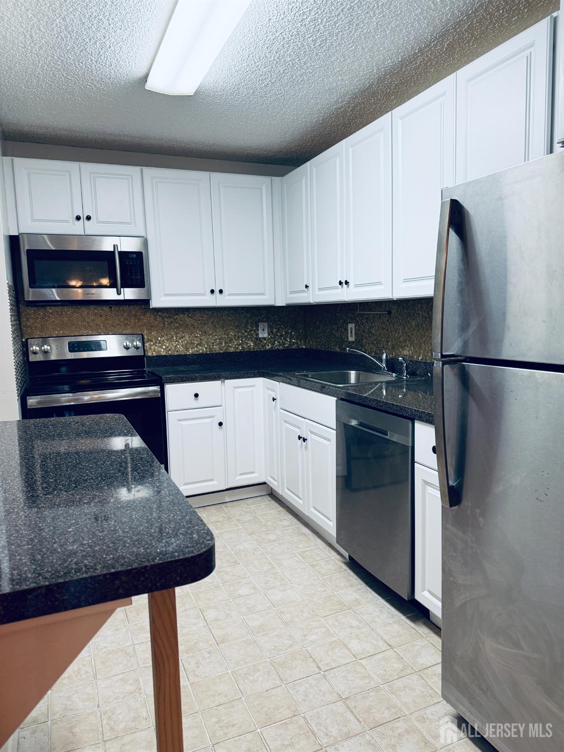 10 North Wood Avenue, Unit 314 Linden, NJ 07036 - Photo 10 of 18 a kitchen with granite countertop a sink stainless steel appliances and white cabinets