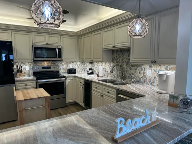 a kitchen with stainless steel appliances granite countertop a stove top oven a sink dishwasher a dining table and chairs with wooden floor