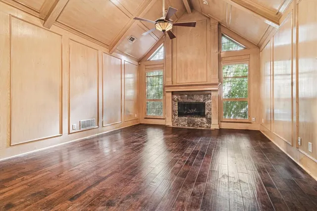 an empty room with wooden floor fireplace and windows