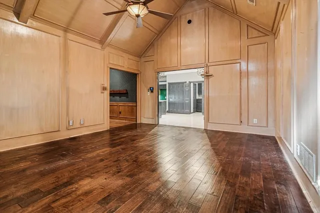 an empty room with wooden floor cabinet and windows