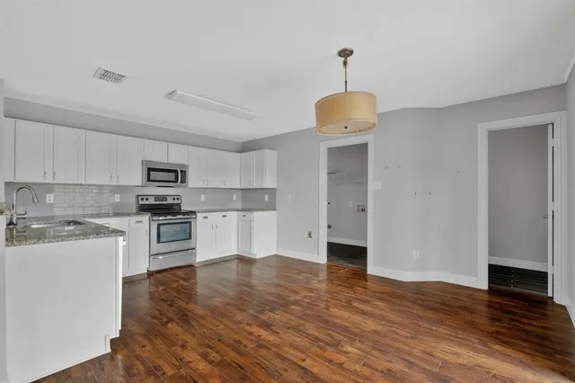 a kitchen with granite countertop a refrigerator and a stove top oven