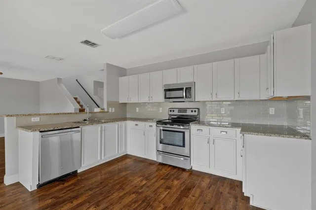 a kitchen with granite countertop a sink dishwasher a stove and a refrigerator with wooden floor