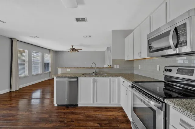a kitchen with stainless steel appliances granite countertop a sink stove and microwave