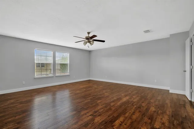 a view of an empty room with a window and wooden floor