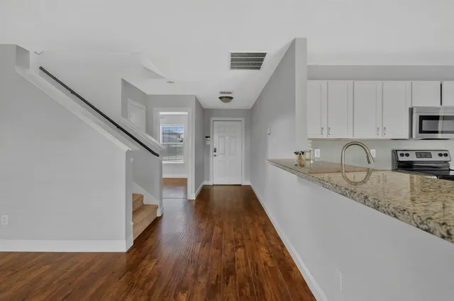 a kitchen with granite countertop a sink and wooden floors