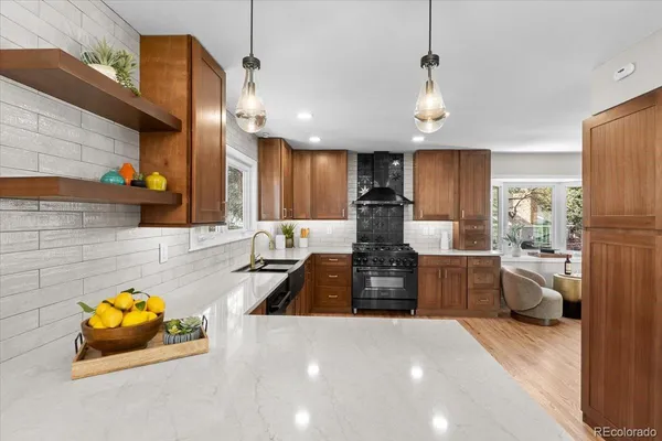 a large kitchen with stainless steel appliances a stove a sink dishwasher and a refrigerator with wooden floor