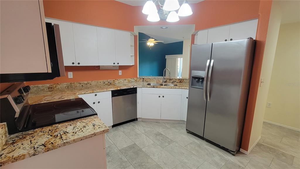 6330 Green Oak Circle, Unit 6330 Bradenton, FL 34203 - Photo 10 of 58 a kitchen with stainless steel appliances granite countertop a refrigerator a sink a stove and a microwave