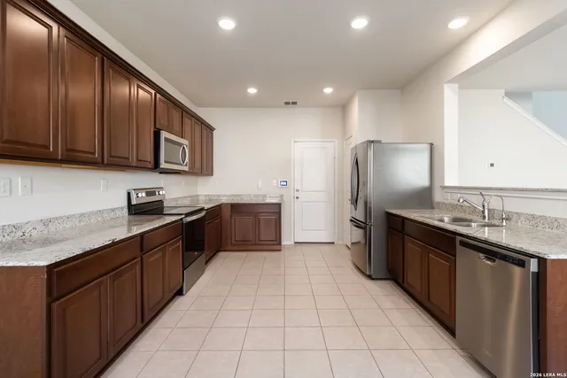 a kitchen with stainless steel appliances granite countertop a sink a stove and a refrigerator