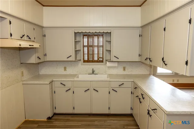 a kitchen with a sink cabinets and wooden floor