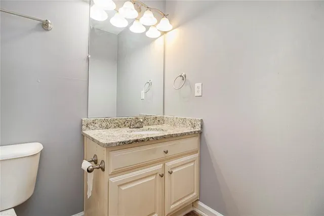 a bathroom with a granite countertop sink a toilet and a mirror