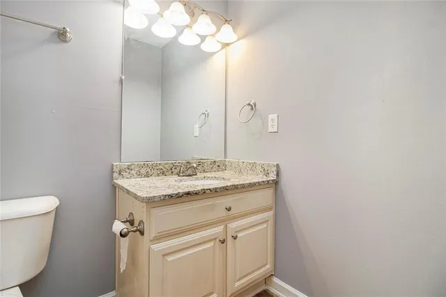 a bathroom with a granite countertop sink a toilet and a mirror