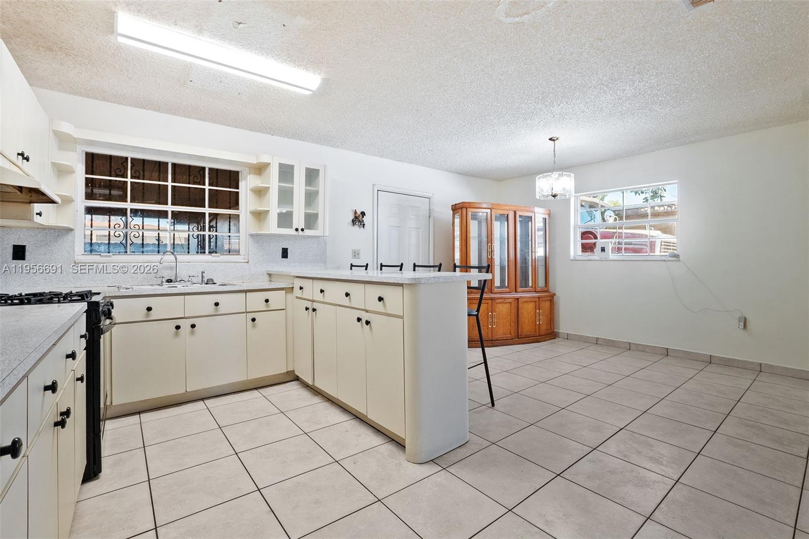 3880 East 8th Lane Hialeah, FL 33013 - Photo 9 of 26 a kitchen with a sink a stove cabinets and counter space