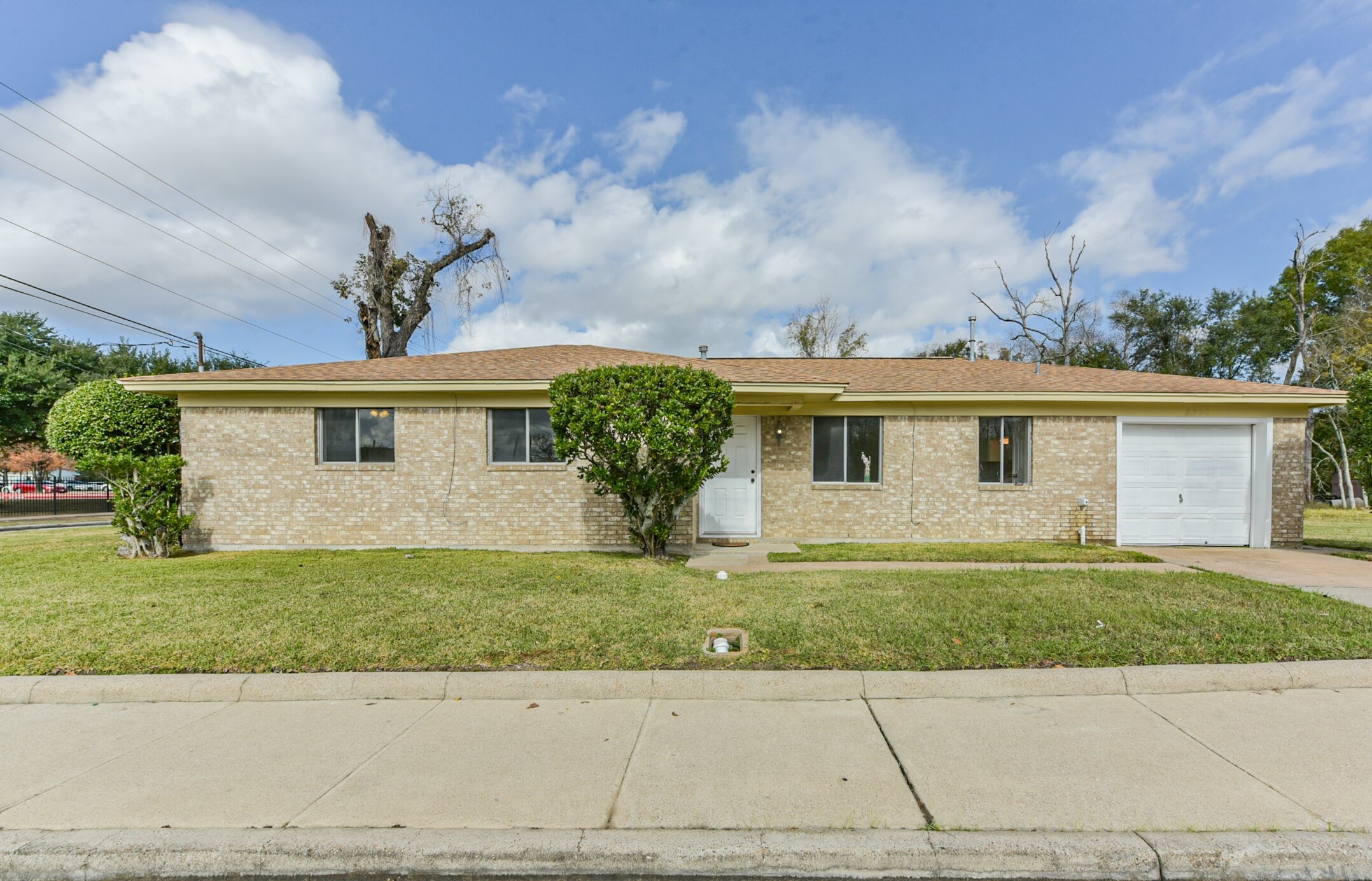 2390 Sarah Street Beaumont, TX 77705 - Photo 2 of 42 This is a single-story brick home with a simple, well-maintained facade. It features a one-car garage and a neatly kept front lawn, offering a clean and straightforward appearance.