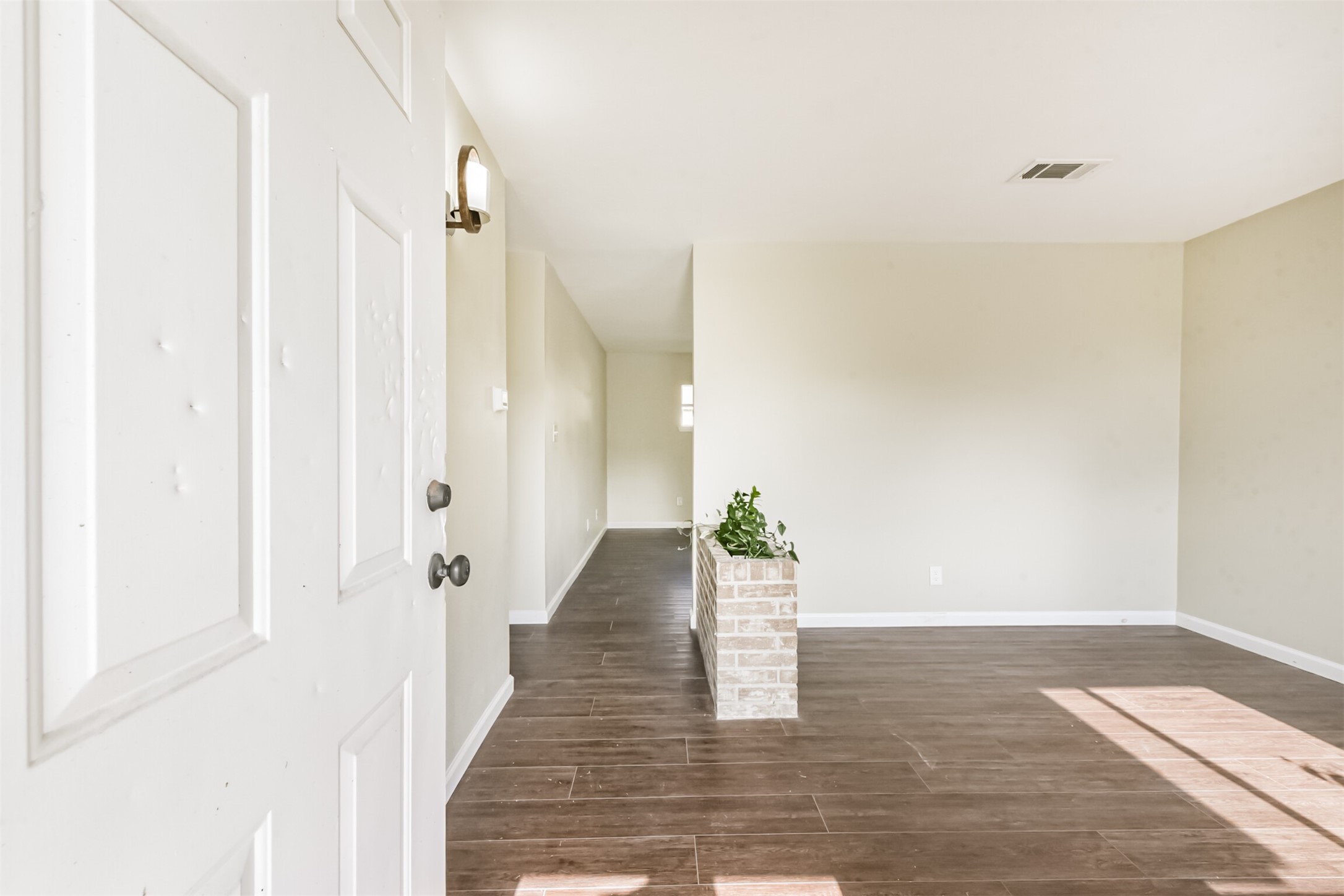 2390 Sarah Street Beaumont, TX 77705 - Photo 4 of 42 Bright and inviting entryway with wood-style flooring, neutral walls, and a small brick planter, offering a spacious and modern feel.