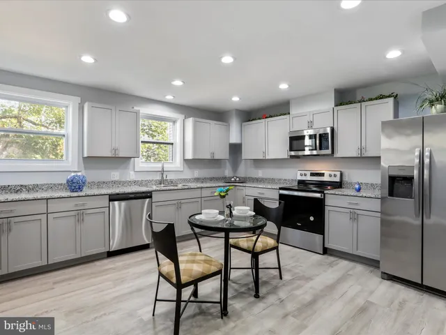 a kitchen with stainless steel appliances granite countertop a stove a sink a refrigerator a microwave oven with a dining table and chairs