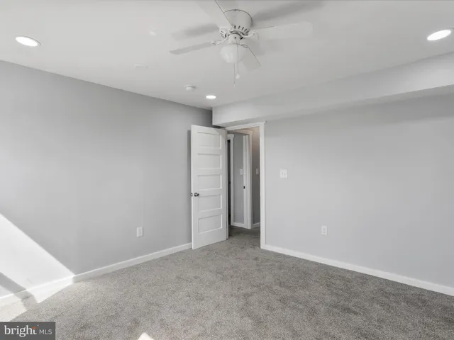 an empty room with a ceiling fan and carpet