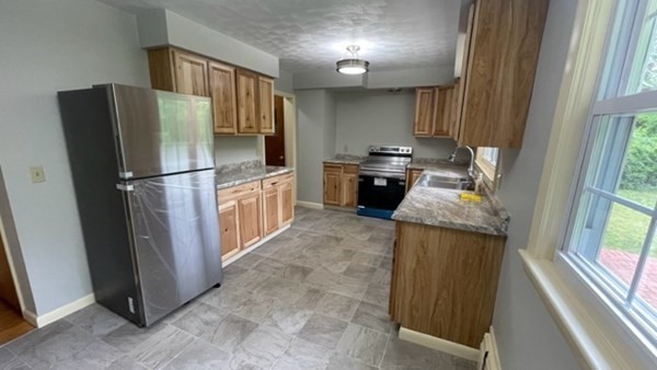 4188 Main Street Palmer, MA 01069 - Photo 9 of 22 a kitchen with granite countertop a refrigerator a stove a sink and a window