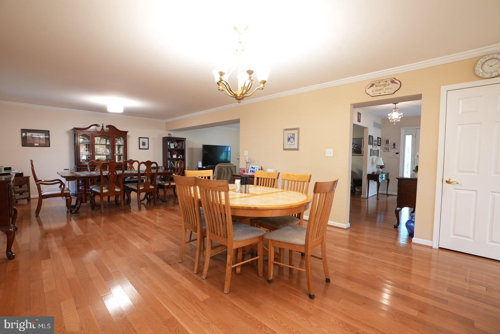 114 Salina Road Sewell, NJ 08080 - Photo 16 of 86 a dining room with wooden floor a chandelier a wooden table and chairs
