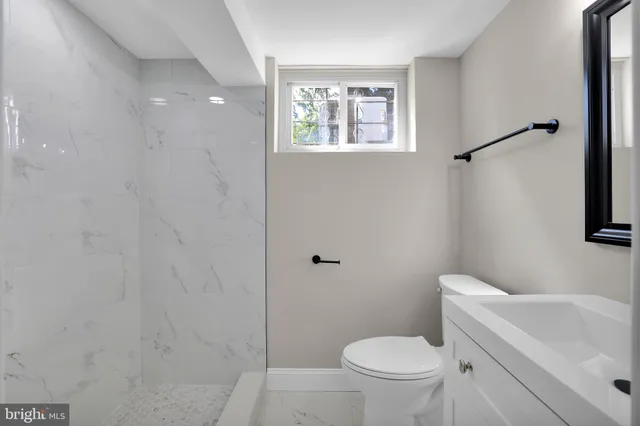 a white toilet sitting next to a white sink and vanity